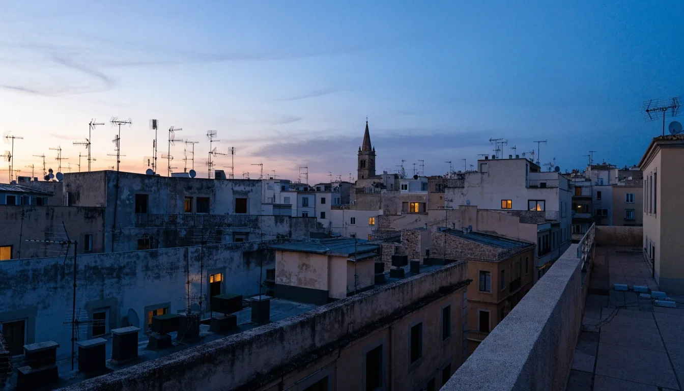 Vista desde una azotea sobre una ciudad balear al anochecer con terrazas y ventanas encendidas